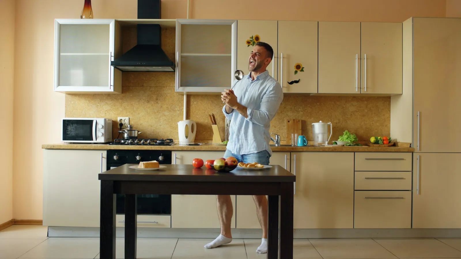 A man singing into a ladle in his kitchen, the everyday hours between training sessions