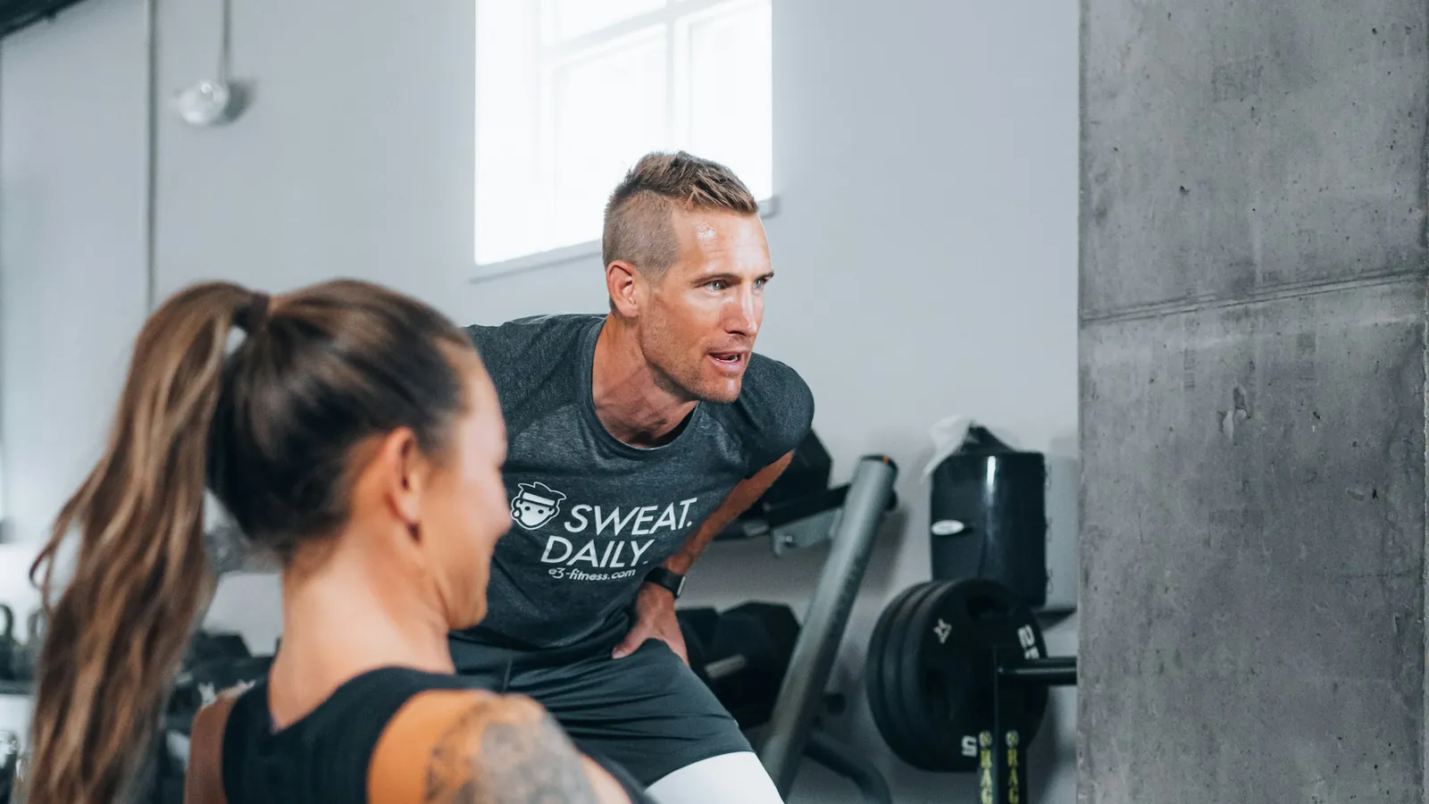 A coach and a client talking through a training plan together in a gym, the setting where a product recommendation is made and repeated