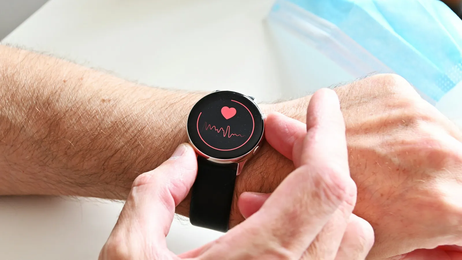 A smartwatch showing a heart-rate reading on a client's wrist