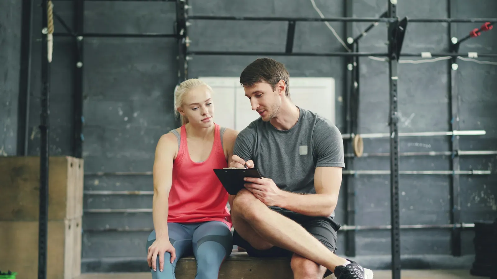 A fitness coach talking with a client during a gym session, the professional recommendation that shapes what clients buy